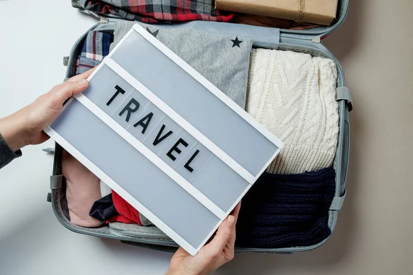 Woman hands with travel board on the background of Open suitcase — Stock Photo, Image