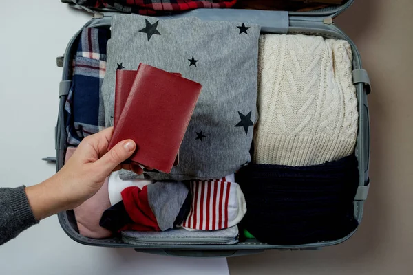 Mani femminili con passaporti sullo sfondo Confezione valigia aperta — Foto Stock