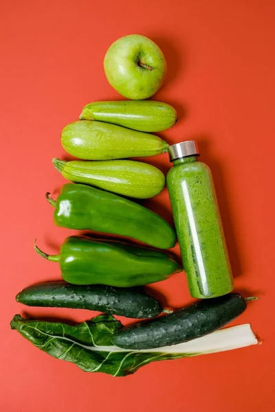 Verduras verdes y batidos en una botella de plástico sobre fondo rojo — Foto de Stock