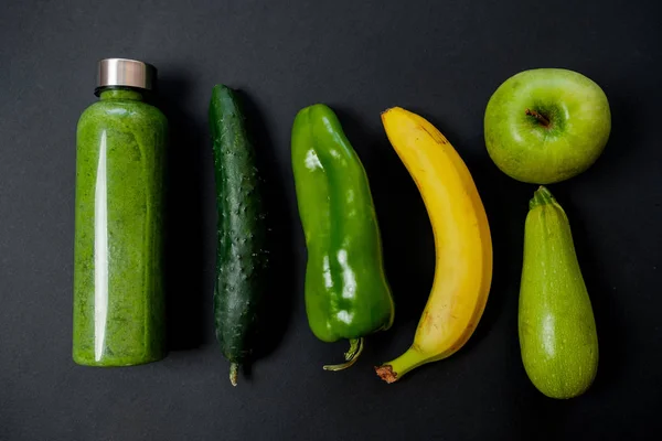Verduras verdes y batidos en una botella de plástico en la espalda negra — Foto de Stock