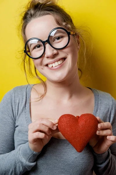 Vacker ung kvinna med ett rött hjärta på gul bakgrund. V — Stockfoto