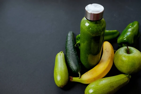 Green vegetables and smoothies in a plastic bottle on black back