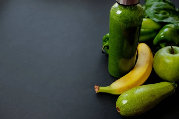 Verduras verdes y batidos en una botella de plástico en la espalda negra — Foto de Stock