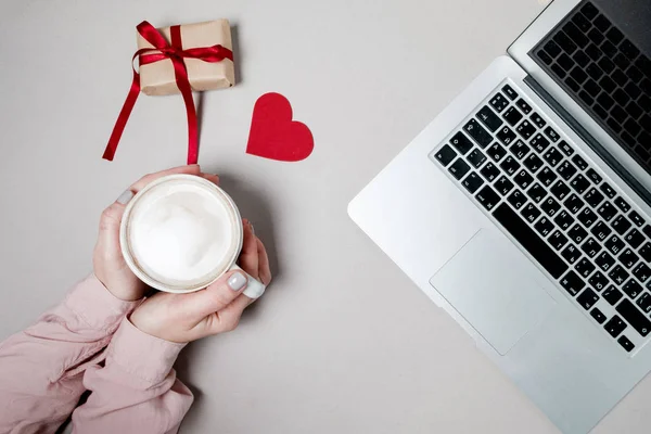 Mãos de mulher com café e laptop, caixa de presente com coração em branco — Fotografia de Stock