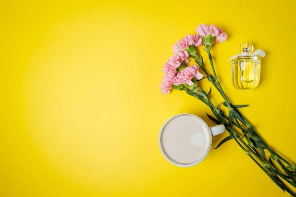 Beker met koffie en roze carnation bloemen, geesten op geel ta — Stockfoto