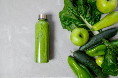 Yeşil sebzeler ve smoothies gri bir arka plan üzerinde plastik şişede. Sağlıklı kavramı. Üstten Görünüm, metin için yer