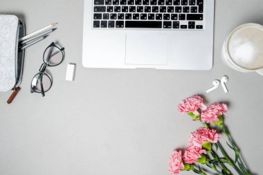 Düz yatıyordu kadın Ofis Masası. Laptop, pembe karanfil, beyaz masa üzerinde ileti örneği ile çalışma alanı. Top vie