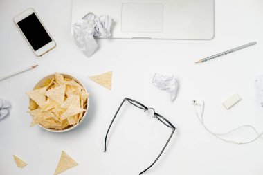 Dizüstü bilgisayar, buruşuk kağıt, ileti örneği ve beyaz masa üzerindeki fişlere çalışma alanı. Kötü alışkanlıkları kavramı