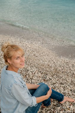 Genç güzel sarışın kadın deniz arka plan üzerinde çizgili gömlekli. Yaz konsepti