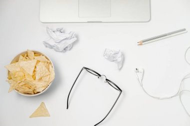 Dizüstü bilgisayar, buruşuk kağıt, ileti örneği ve beyaz masa üzerindeki fişlere çalışma alanı. Kötü alışkanlıkları kavramı