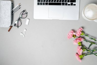 Düz yatıyordu kadın Ofis Masası. Laptop, pembe karanfil, beyaz masa üzerinde ileti örneği ile çalışma alanı. Top vie