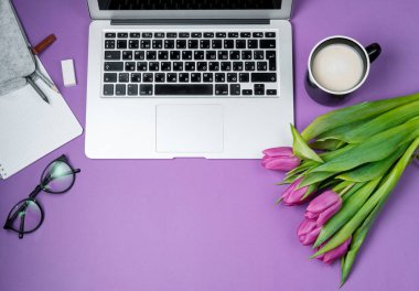 Laptop ile sabah kahvesi ve Lale Menekşe arka plan üzerinde. Düz lay, Bahar tatili. Anneler günü