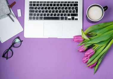 Laptop ile sabah kahvesi ve Lale Menekşe arka plan üzerinde. Düz lay, Bahar tatili. Anneler günü