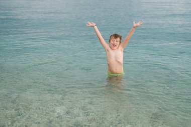 Neşeli mutlu çocuk denizde elleriyle ayağa kalkar. Yaz c