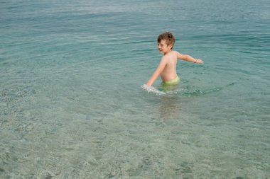 Neşeli mutlu çocuk denizde elleriyle ayağa kalkar. Yaz c