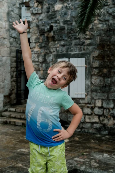 Милый мальчик в зеленой футболке против старого города — стоковое фото