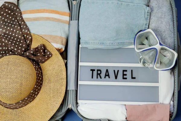 Travel board in Open suitcase packed with clothes. Summer vacati — Stock Photo, Image