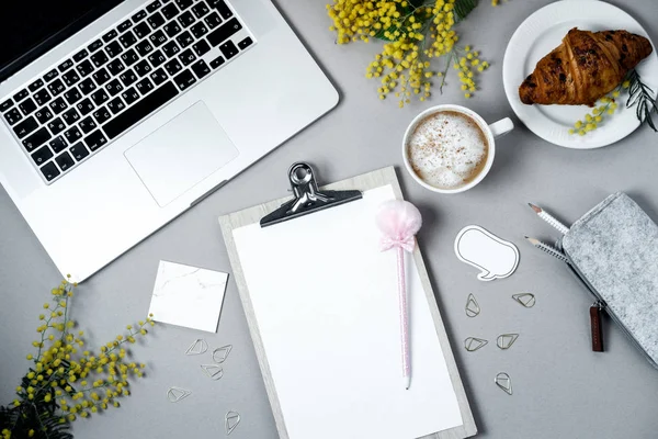 Жінка працює простір з ноутбуком, квітка мімози, круасан, кава — стокове фото