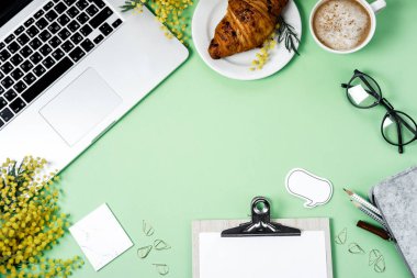 Kadın çalışma alanı laptop, Mimoza çiçeği, kruvasan, kahve ile bir