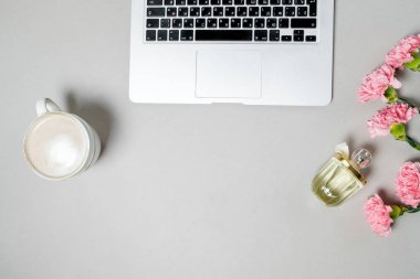 Düz yatıyordu kadın Ofis Masası. Dizüstü bilgisayar, pembe carnatio ile çalışma alanı