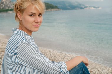 Deniz arka plan üzerinde çizgili gömlekli sarışın genç güzel kadın.