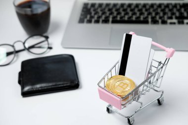Bitcoin ve beyaz masa üzerinde kredi kartı ile alışveriş sepeti. Crypt