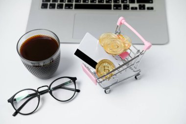 Bitcoin ve beyaz masa üzerinde kredi kartı ile alışveriş sepeti. Crypt