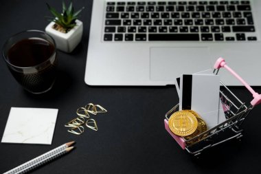 Bitcoin ve siyah masa üzerinde kredi kartı ile alışveriş sepeti. Crypt