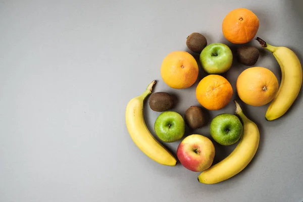 Colorida fruta fresca en la mesa Gray. Naranja, plátano, manzanas, kiwi — Foto de Stock