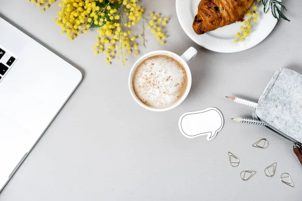 Espaço de trabalho da mulher com laptop, flor de mimosa, croissant, café a — Fotografia de Stock