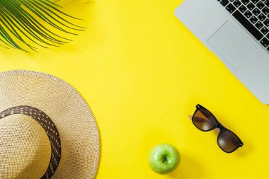 Çalışma alanı: Laptop, palmiye yaprağı, sarı bir arka pano şapka