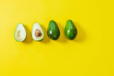 Sarı bir arka plan üzerinde birkaç dilimlenmiş avokado. Üstten Görünüm, düz yatıyordu