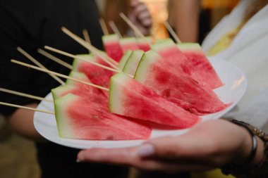 Partide bir tabak doğranmış karpuzla kadın eli.