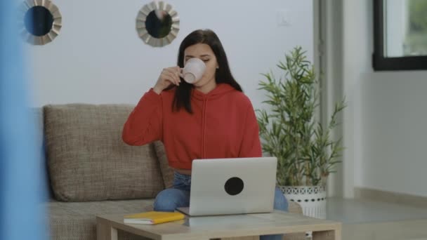Milenyum Esmer Kırmızı Kapüşonlu Kadın Kahve Içiyor Mesaj Yazıyor Bilgisayarında — Stok video