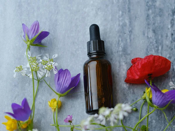 Glazen Fles Met Gezichtsolie Wilde Bloemen Een Marmeren Bord Bovenaanzicht — Stockfoto