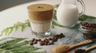 Dalgona kahvesi badem sütü ve esmer şeker, kahve çekirdekleri ve mermer tahtada yeşil bitki. Krem şantili, modaya uygun bir Kore içeceği.. 