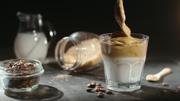 アーモンドミルクと黒糖 黒を背景にコーヒー豆とダルゴナコーヒーを作る ホイップクリームとともに流行のふわふわ韓国ドリンクのグラス — ストック動画