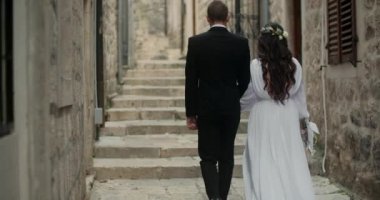Avrupa 'da yürüyen güzel beyaz elbiseli ve damat, Karadağ' da el ele tutuşan romantik düğün çifti.