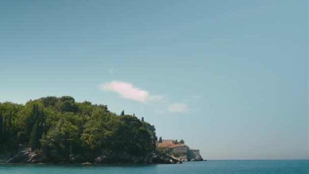 モンテネグロの紺碧の水と海の海岸ペブルビーチから晴れた日にスヴェティ シュテファン島での眺め — ストック動画