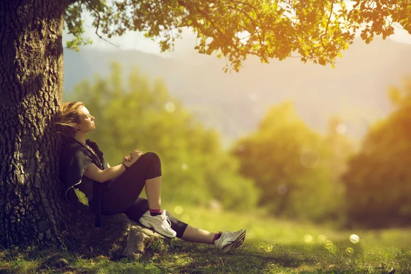 Belle fille se détendre sous un arbre par une journée d'été ensoleillée Images De Stock Libres De Droits