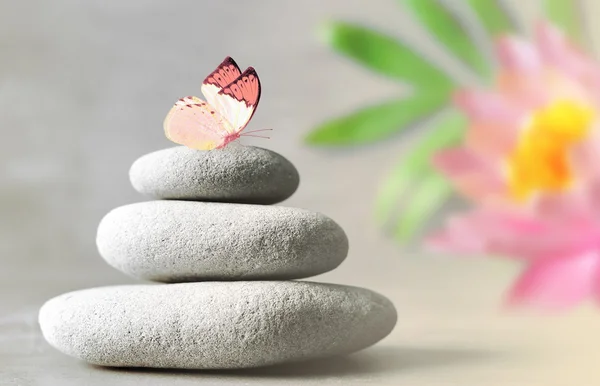 Wellness-Steine mit Blütenlilie auf hellem Hintergrund — Stockfoto