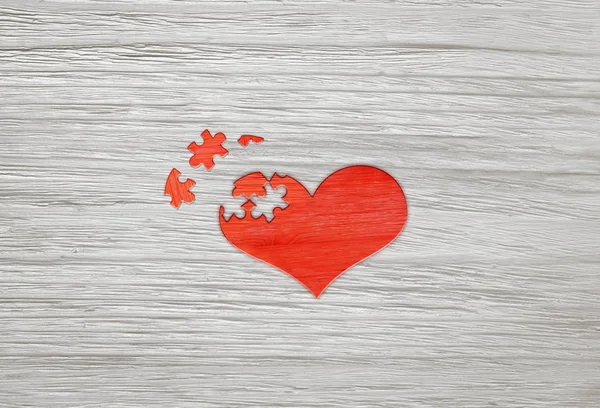 Cœur de puzzle en bois rouge sur fond gris — Photo