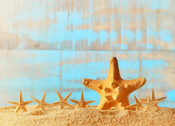 Arena marina con estrellas de mar sobre fondo de madera . — Foto de Stock