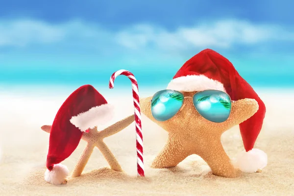 Starfish in sunglasses on summer beach and santa hat. — Stock Photo, Image