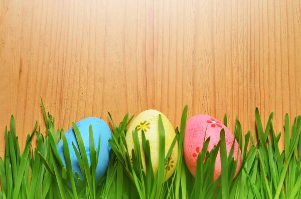 Huevos de Pascua pintados en una hierba verde sobre un fondo de madera . — Foto de Stock