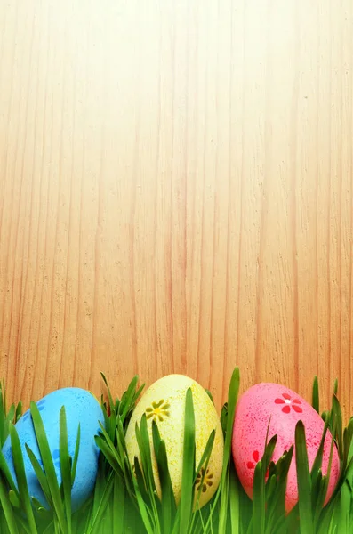 Œufs de Pâques peints dans une herbe verte sur un fond en bois . — Photo