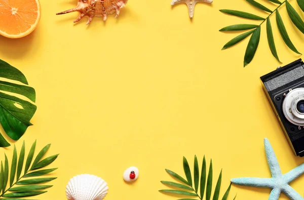 Tropische achtergrond. Palm bomen takken met camera en zeeschelp op gele achtergrond. Reizen. Kopiëren van ruimte. — Stockfoto