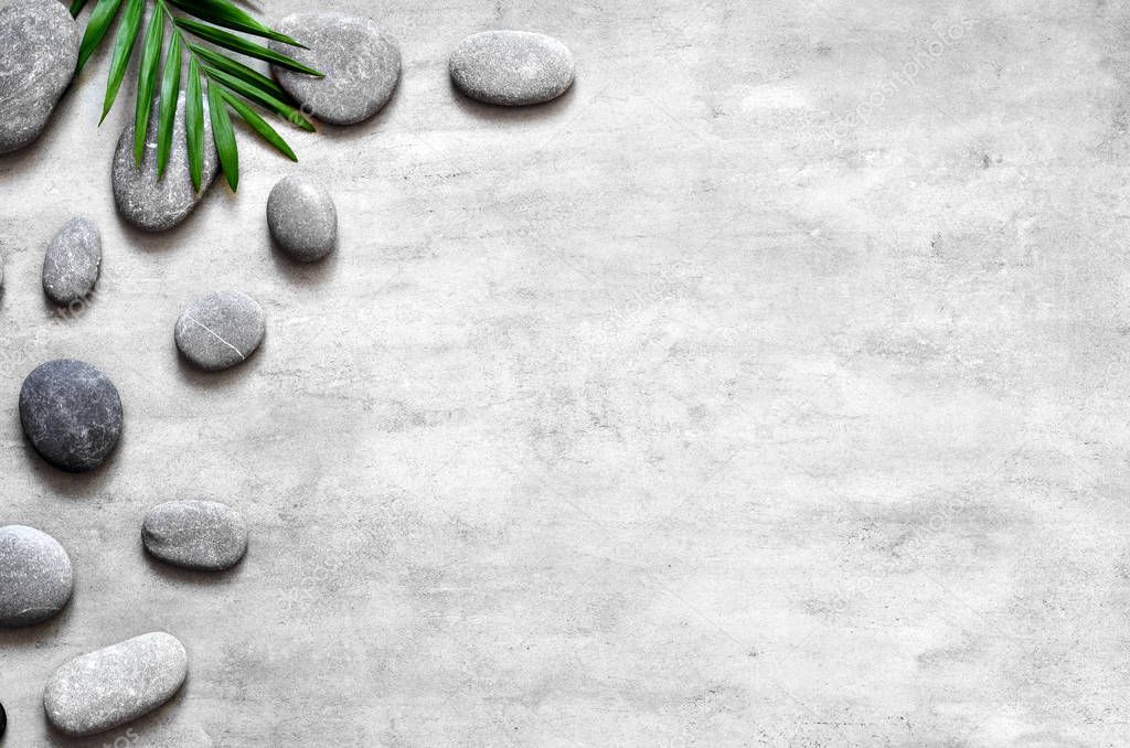 Grey spa background, palm leaves and grey stones, top view