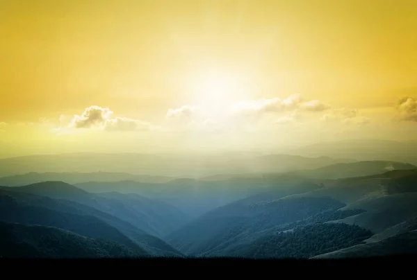 Piękny krajobraz w górach o wschodzie słońca. Widok mglisty wzgórza pokryte przez las. Filtrowanego obrazu: krzyż przetwarzane efekt retro — Zdjęcie stockowe