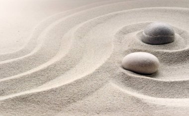 Zen bahçesi meditasyon taşı arka planında rahatlama dengesi ve ahenk ruhsallığı veya spa sağlığı için kumdaki taşlar ve çizgiler var.